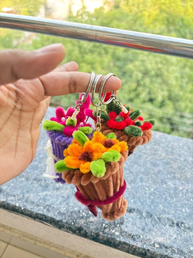 Bloom Bouquet Keychain. Handcrafted mini bouquet keychain made from soft chenille wire, with colorful flowers and green leaves in a wrapped cone base. Comes in assorted colors. A cute add-on for keys or bags.