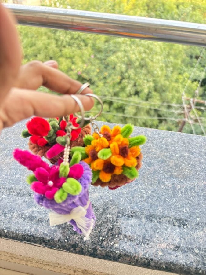 Pearl Posy Keychain. Handcrafted mini bouquet keychain made from soft chenille wire, with bright flowers, green leaves, and a pearl accent. Wrapped in a ribbon-tied cone, in assorted colors. A cute add-on for keys or…